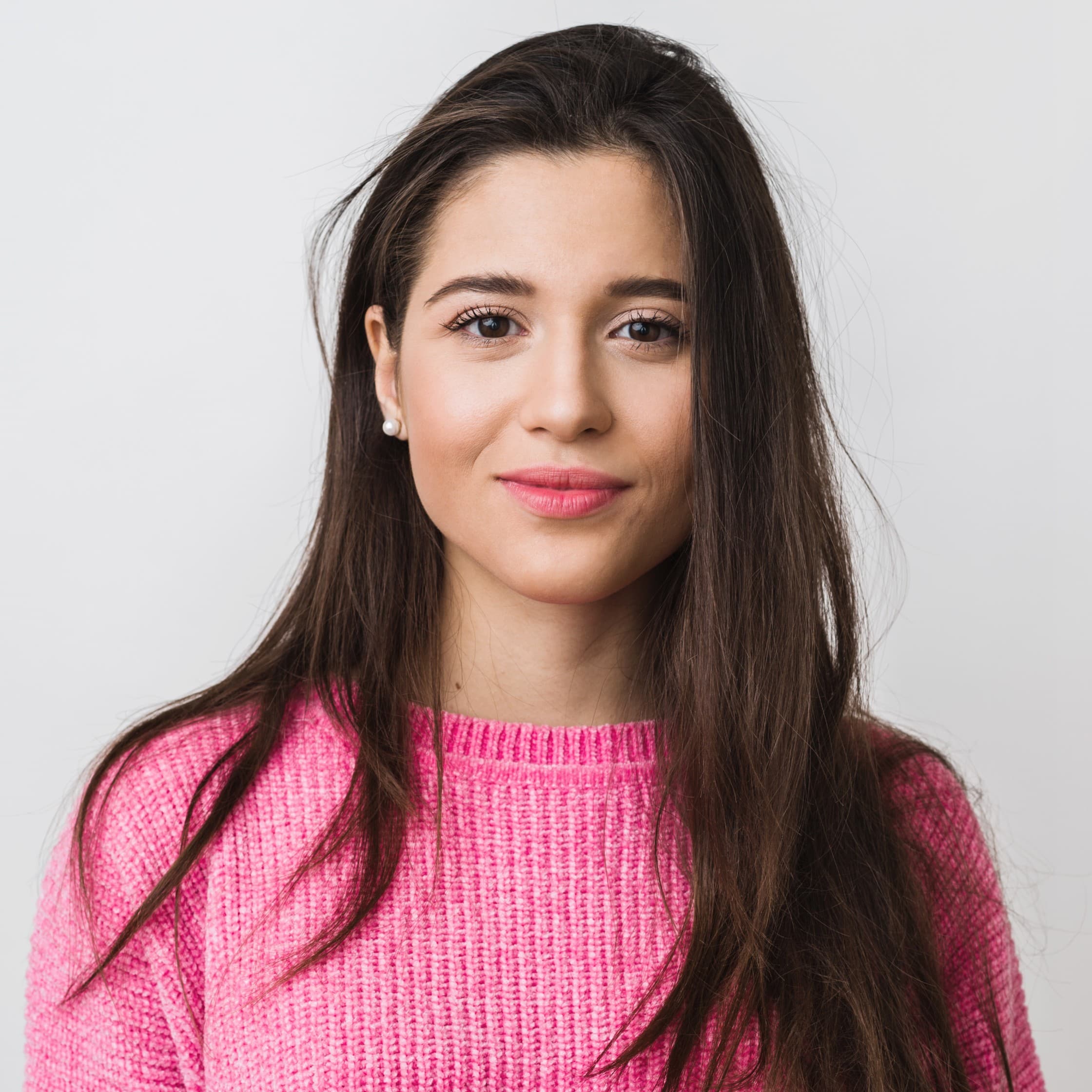 woman in a pink sweater with dark long hair smiling