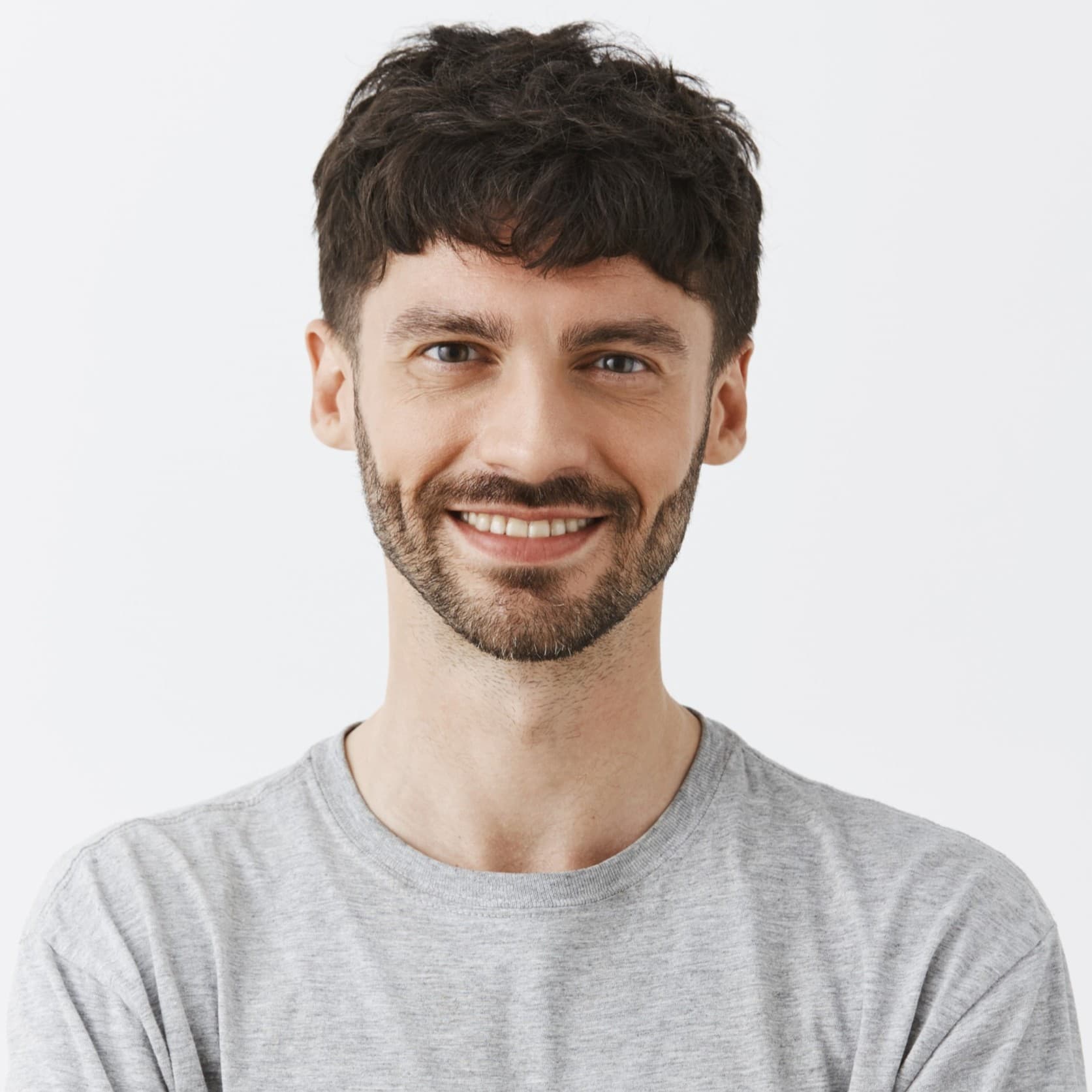 A man with short dark hair, a beard and a mustache in a gray T-shirt, smiling